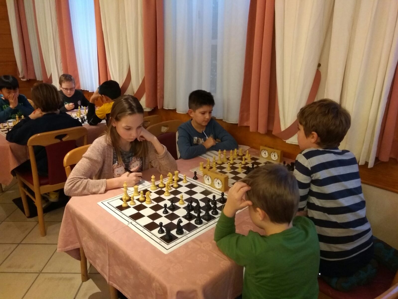 Kinder an mehreren Schachbrettern bei einem Jugendliga-Spieltag
